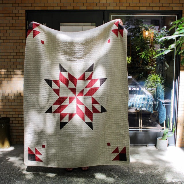 Beige patchwork quilt cover with bold red and dark red star pattern, vintage British mid-century style.