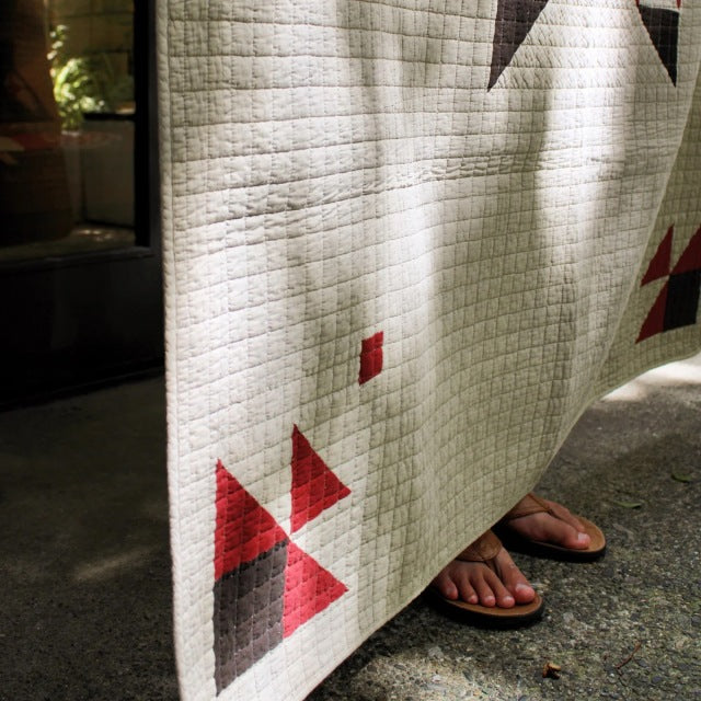 Beige patchwork quilt cover with red and brown geometric vintage-inspired design, showcasing textured stitching.