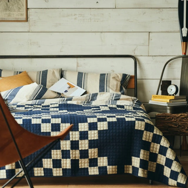 Mid-century teak bed frame with rounded black metal headboard and footboard, featuring British vintage-inspired patchwork.