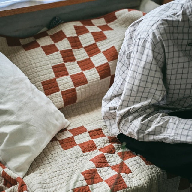 Vintage teak mid-century British sofa with visible wood grain and a red patterned patchwork quilt cover labeled Basshu.