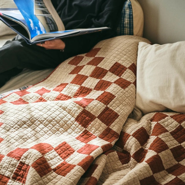Red and beige patchwork quilt with a vintage British mid-century style, featuring a detailed stitched pattern and soft.