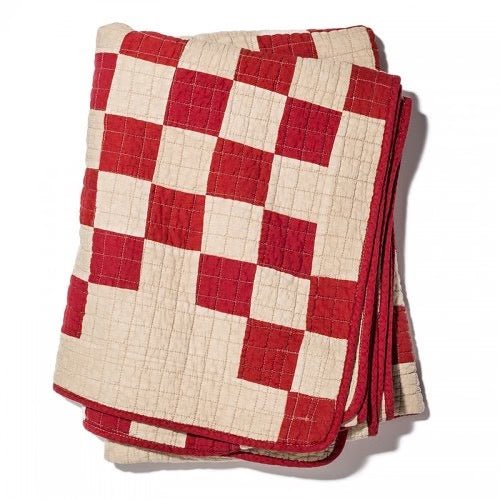 Folded red and beige patchwork quilt cover with a vintage British mid-century style design.