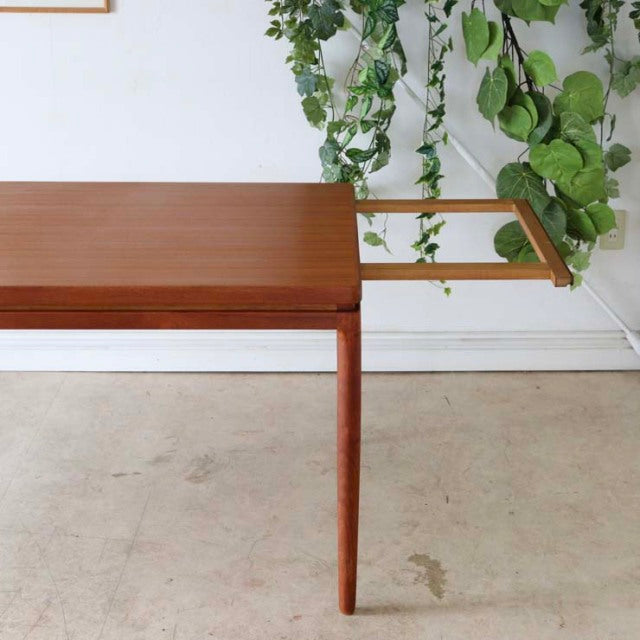 Mid-century vintage teak dining table by Johannes Andersen, slim rectangular top with rich wood grain and slender tapered.