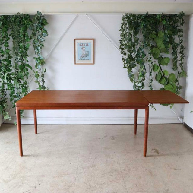 Mid-century vintage Danish teak dining table with rectangular top and slender tapered legs, rich wood grain visible, elegant .