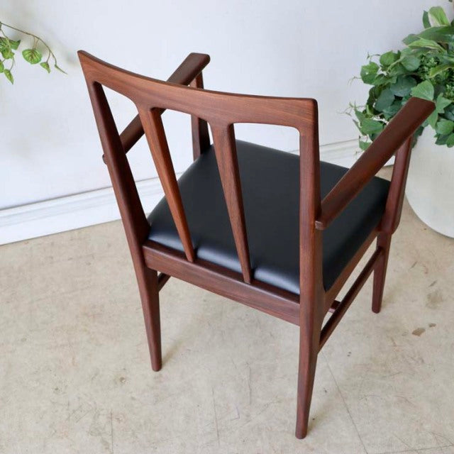Mid-century British teak dining chair by John Herbert with black upholstered seat and sculpted armrests, showcasing elegant.