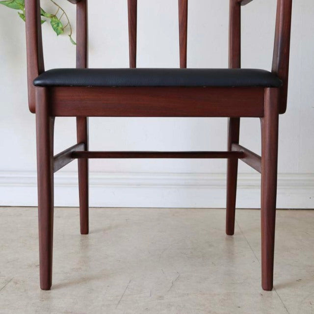 Vintage teak dining chair with British mid-century design, black seat cushion, slender legs, and armrests.