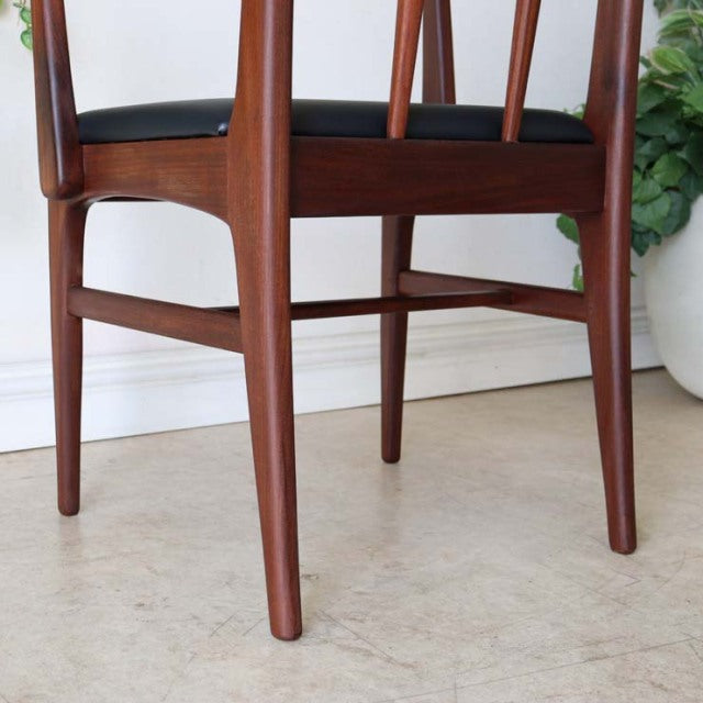 Mid-century British teak dining chair by Younger with armrests, visible wood grain, tapered legs, and black upholstered.