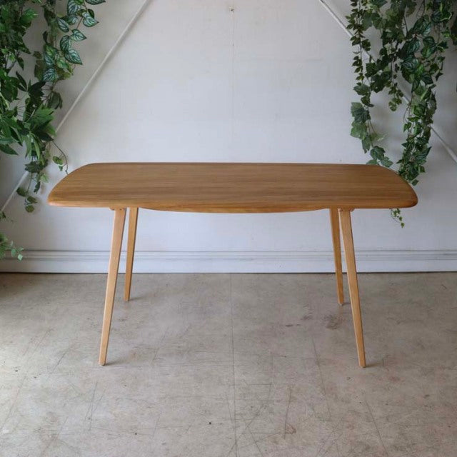 Mid-century British vintage Ercol dining table in teak with smooth rounded rectangular top and slender tapered legs.