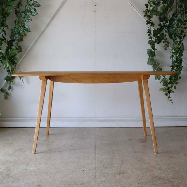 Mid-century British Ercol dining table in teak with clean rectangular top, smooth wood grain, and slender tapered legs.