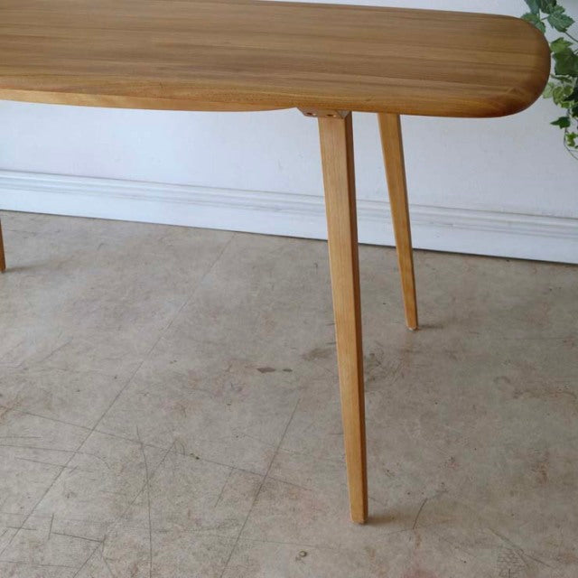Mid-century British Ercol dining table in vintage teak with rounded edges and slender tapered legs showing warm wood grain.