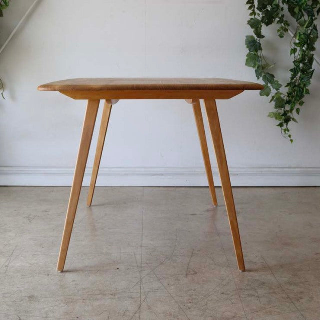 Mid-century British vintage Ercol dining table in teak with rounded rectangular top and angled slender legs showing rich.