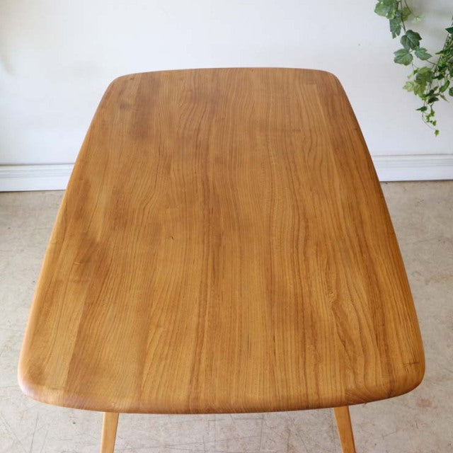 Vintage mid-century British Ercol dining table in teak with smooth rounded edges and visible wood grain on rectangular top.