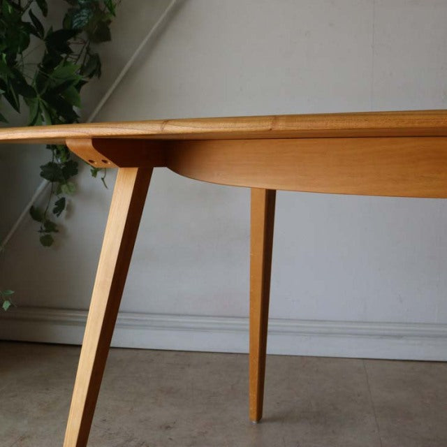 Mid-century British Arcol dining table in warm teak with visible wood grain and slender tapered legs.