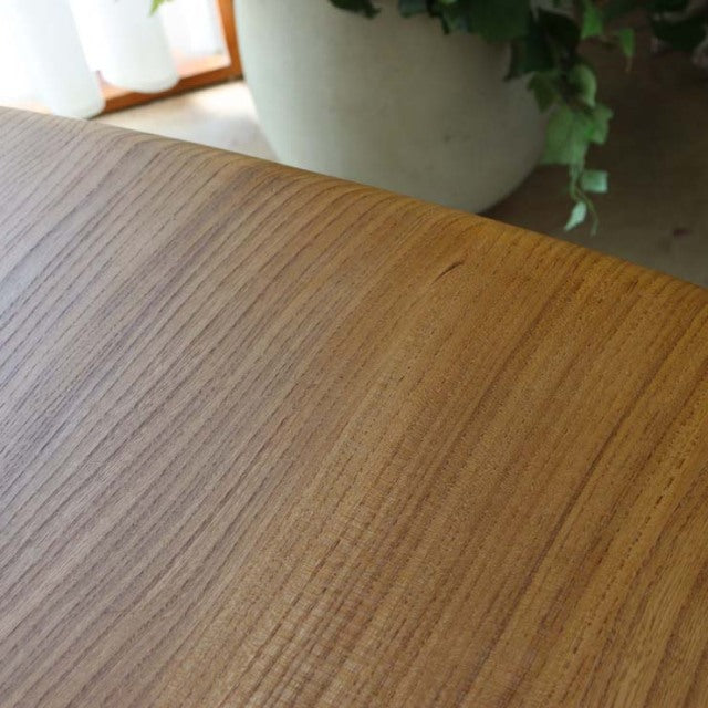Close-up of vintage British mid-century Ercol dining table showcasing smooth teak wood grain and rounded rectangular edge.