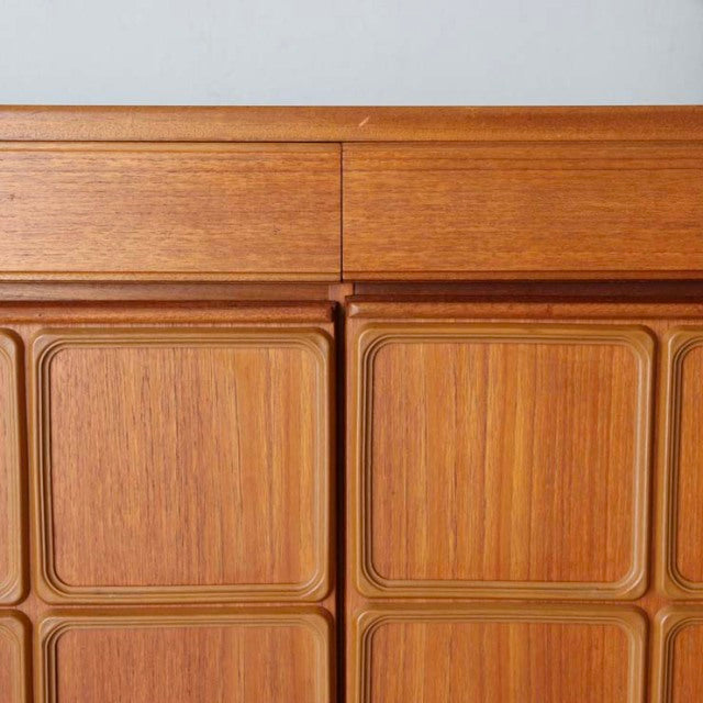 Vintage British McIntosh teak sideboard with sleek mid-century design, textured wood grain, and sculpted drawer fronts.