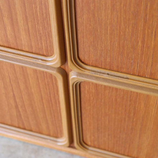 Close-up of vintage British McIntosh mid-century teak sideboard door edges showcasing smooth wood grain and rounded corner.