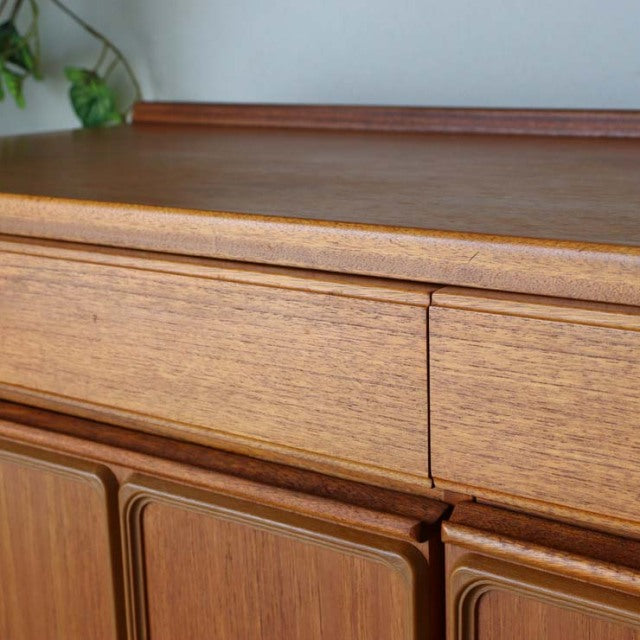 Vintage British McIntosh mid-century teak sideboard featuring rich wood grain, sleek drawers, and smooth rounded edges.