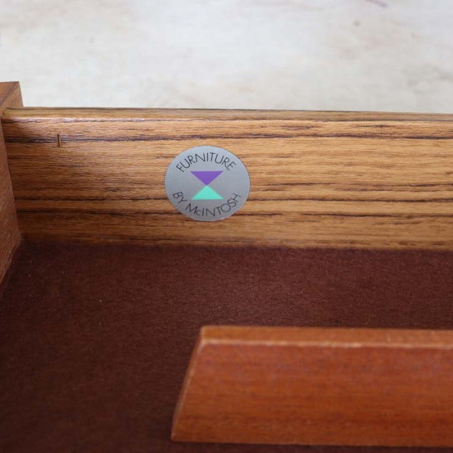 Close-up of vintage British McIntosh teak sideboard interior showing rich wood grain and original brand metal label on.