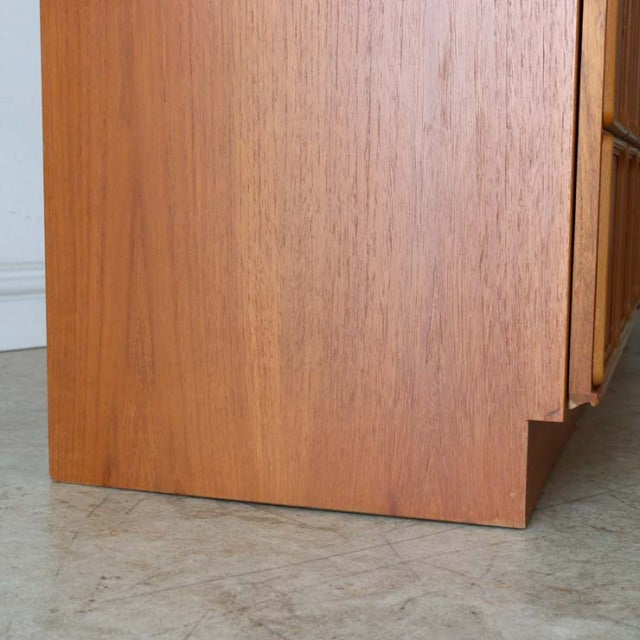 Mid-century British McIntosh teak sideboard detail showing warm wood grain and clean lines on stepped corner leg.