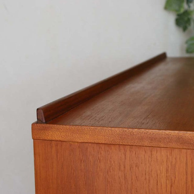 Vintage British McIntosh mid-century teak sideboard top corner showing warm wood grain and clean lines.