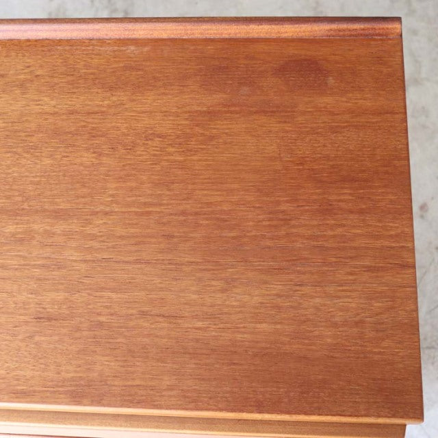 Close-up of vintage British McIntosh teak sideboard top showing smooth wood grain and mid-century craftsmanship.