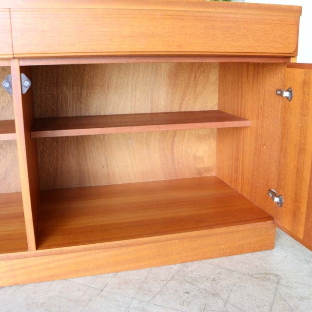 Mid-century British McIntosh teak sideboard interior with wood grain, adjustable shelf, and sleek hinges.