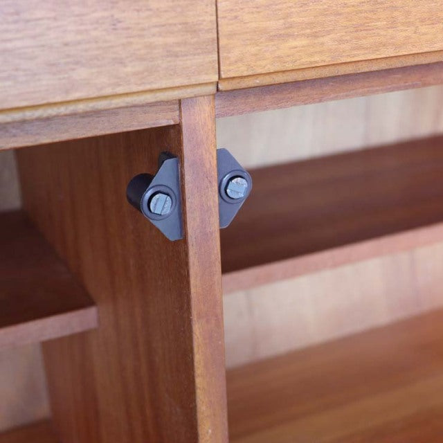 Close-up of mid-century British McIntosh teak sideboard interior with wood grain and black metal hinges.