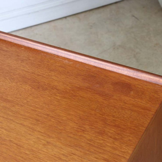 Mid-century British McIntosh teak sideboard corner showing rich wood grain and smooth finish.