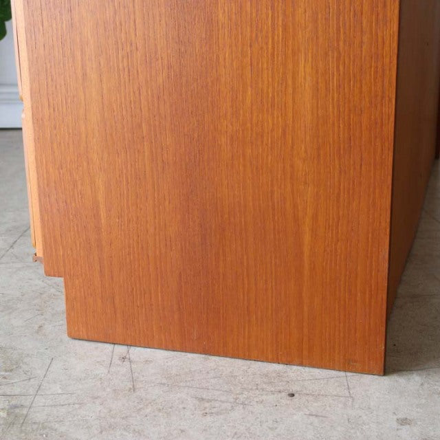Close-up of vintage British McIntosh teak sideboard corner showing smooth wood grain and mid-century Danish design legs.