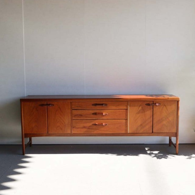 Vintage mid-century teak sideboard by British brand Nathan with clean lines, wood grain detail, tapered legs, and three.