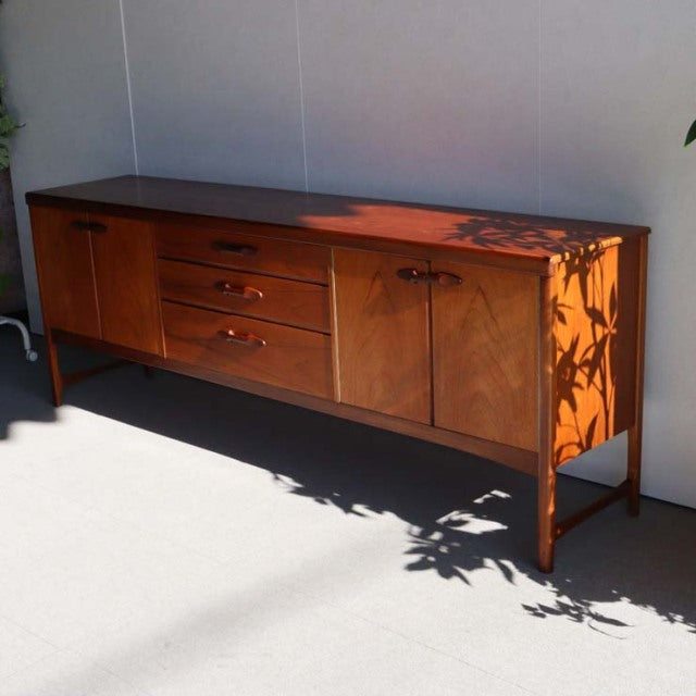 Mid-century British Nathan teak sideboard from Denmark with rich wood grain, tapered legs, and three drawers flanked by two.