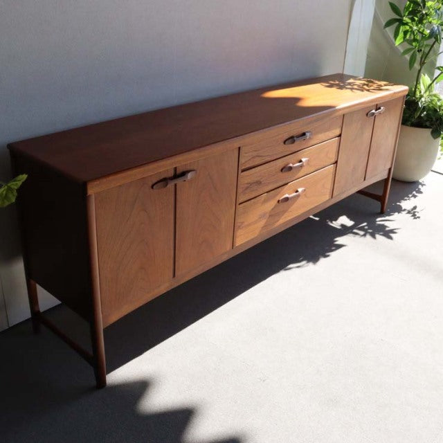 Vintage teak sideboard by British brand Nathan, mid-century design with clean lines, wood grain visible, tapered legs, and.