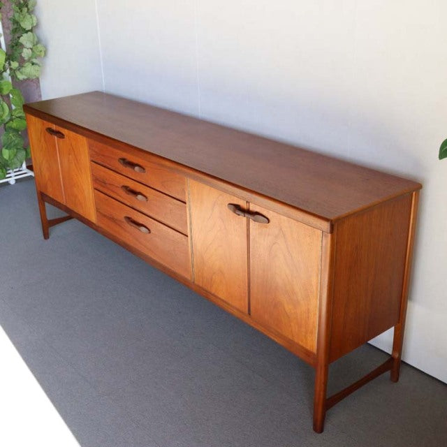 Vintage teak mid-century sideboard by British brand Nathan, featuring clean lines, wood grain doors, three central drawers,.