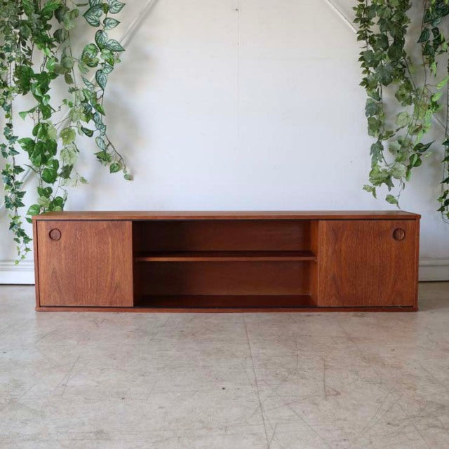 Vintage British mid-century Avalon teak lowboard with rich wood grain, sliding doors, and open shelving.