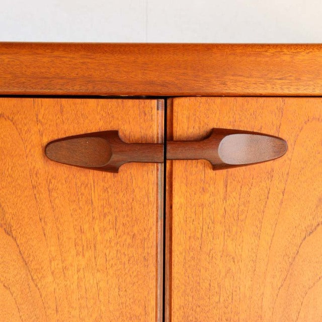 Close-up of vintage teak sideboard doors by Nathan, showcasing smooth wood grain and mid-century British design handles.
