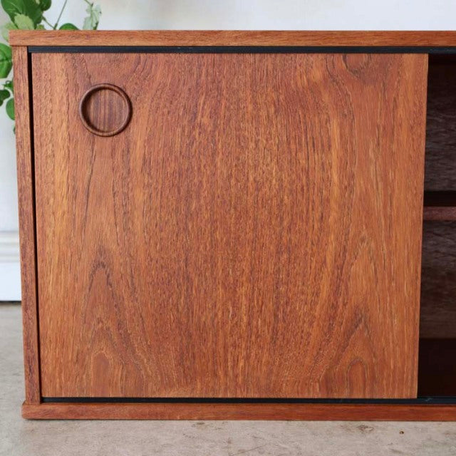 Mid-century British vintage teak lowboard by Avalon with rich wood grain and circular recessed handle on sliding door.