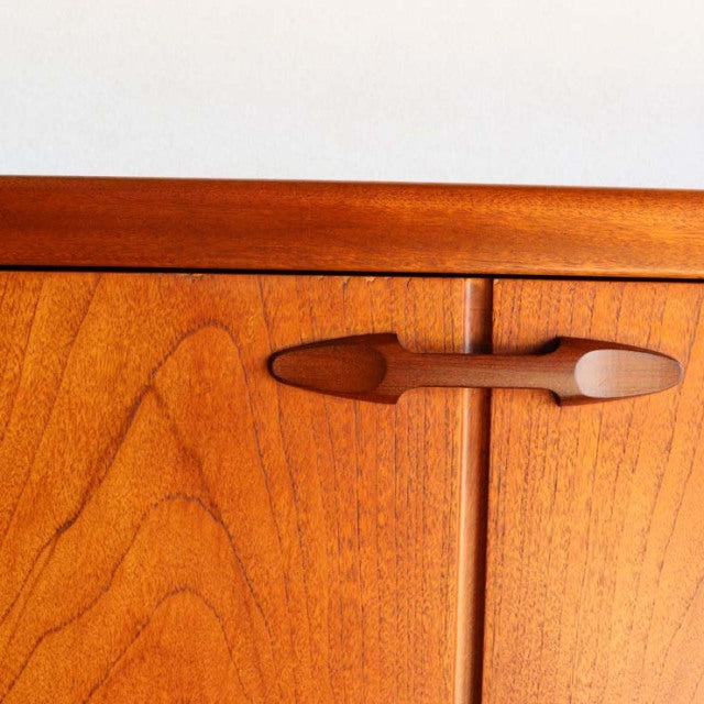 Close-up of vintage teak sideboard by British brand Nathan, mid-century design with smooth wood grain and sculpted wooden.