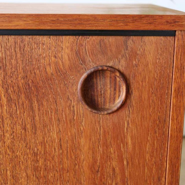 Close-up of vintage teak cabinet door from British Avalon lowboard, featuring circular recessed handle and mid-century wood.
