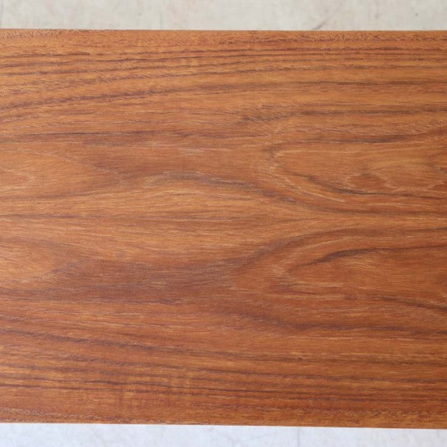 Close-up of vintage teak wood grain on British mid-century Avalon lowboard, smooth polished surface.