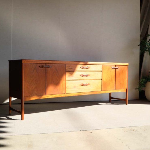 Mid-century teak sideboard by Nathan, British craftsmanship with warm wood grain, slender legs, and functional drawers.