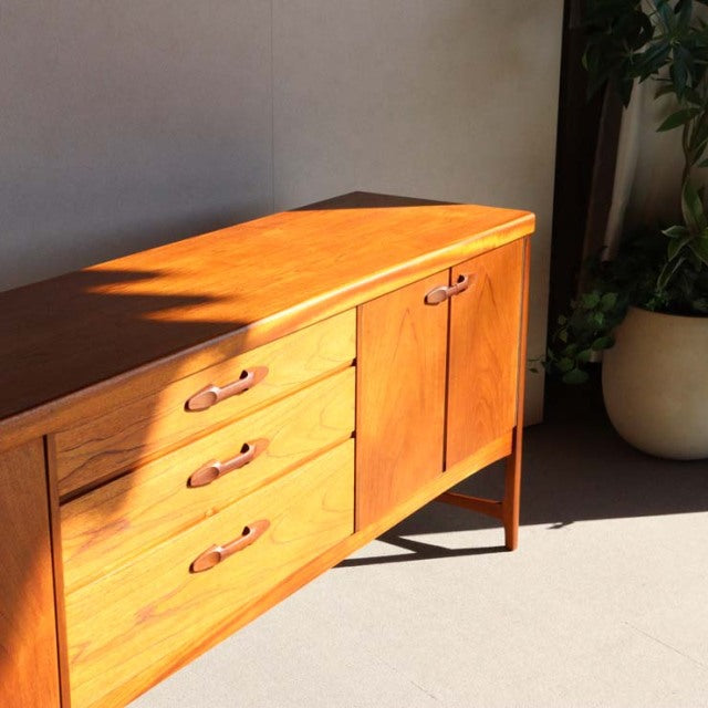 Vintage teak sideboard by Nathan, British mid-century style with smooth wood grain, three drawers, double door cabinet, and.