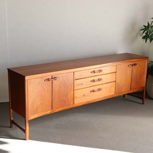 Vintage teak mid-century sideboard by British brand Nathan, featuring wood grain, three central drawers, and two cabinet.