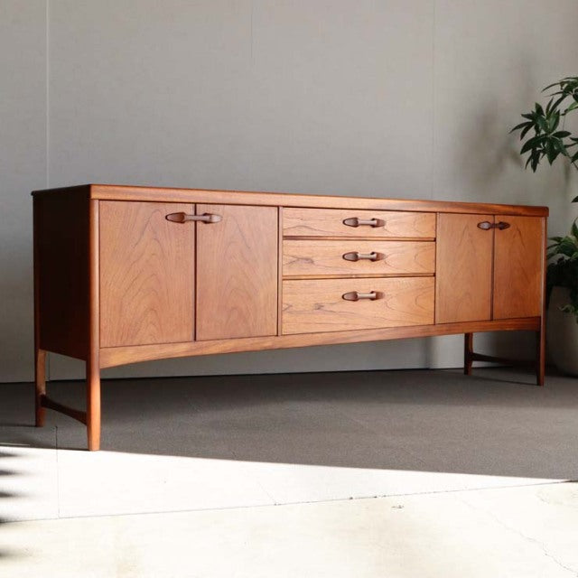 Mid-century British vintage teak sideboard by Nathan, sleek wood grain, raised legs, minimalist handles, and clean.