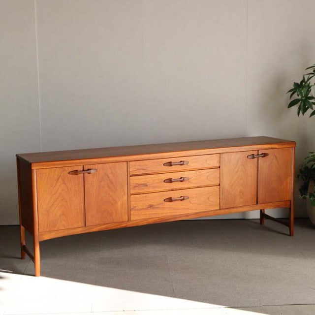 Mid-century British teak sideboard by Nathan with four central drawers and two side cabinets, sleek wood grain, tapered.