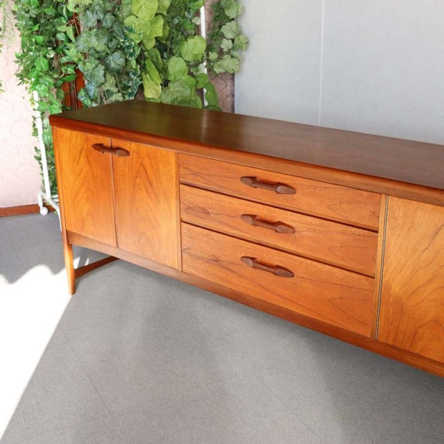 Vintage teak sideboard by Nathan, British mid-century design with rich wood grain, tapered legs, and three drawers flanked.