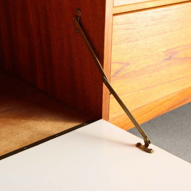 Mid-century British Nathan teak sideboard door with brass support hinge, showing rich wood grain and smooth finish.