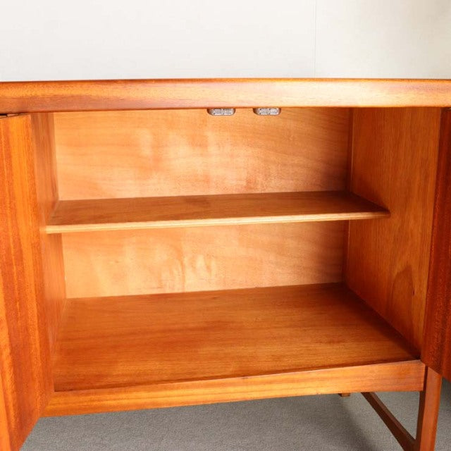 Mid-century teak sideboard by Nathan with rich wood grain, open shelving, and slender tapered legs, British-Denmark vintage.