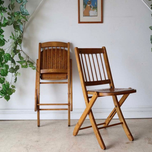 Set of two vintage teak folding chairs with slatted backs, British mid-century design, clean lines showcasing natural wood.