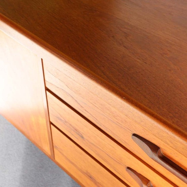 Vintage teak sideboard by Nathan with smooth wood grain, mid-century British design, and sculpted handles.
