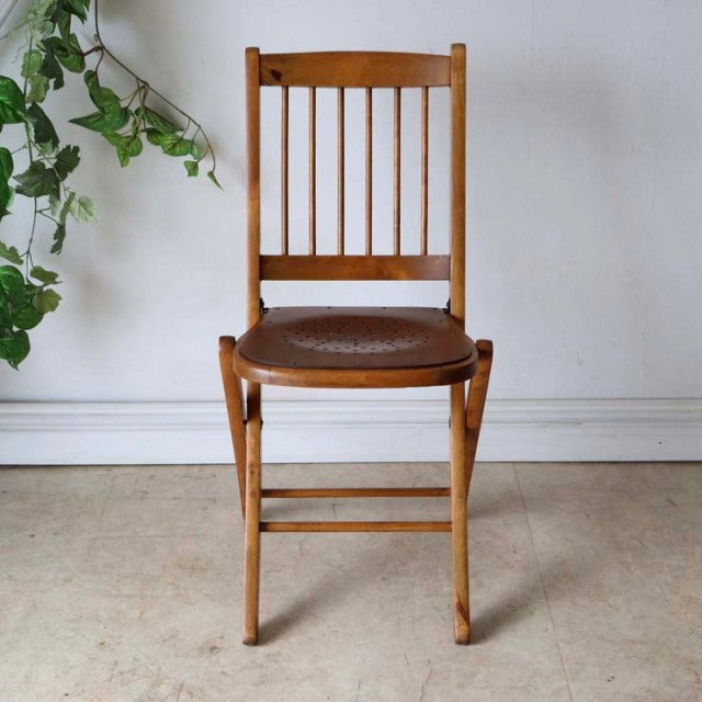 Vintage British teak folding chair with a slatted backrest and smooth leather seat, mid-century Denmark style, showcasing.
